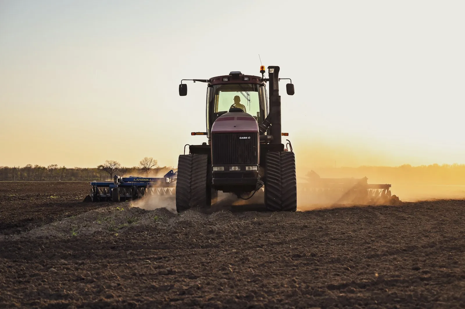 A tractor working a field at sunset